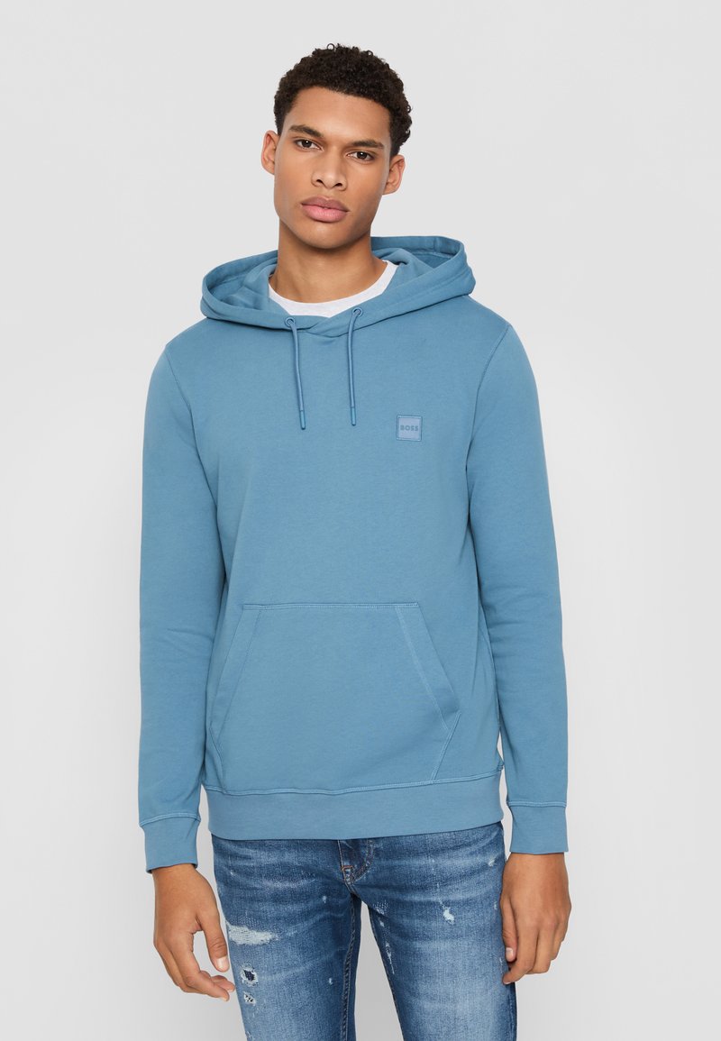 Blauwe hoodie gemaakt van zachte stof, met een kangoeroezak, geribbelde manchetten en een klein logo-label op de borst.