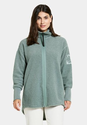 Fleece jacket in muted green, featuring a zip front, high collar, and contrasting cuffs. Soft, textured fabric with a relaxed fit.