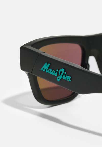Ochelari de soare negri cu un finisaj mat, având lentile de culoare portocalie și branding-ul albastru "Maui Jim" pe lateral. Cadru de formă pătrată.