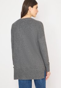 Maglione grigio in maglia con finitura testurizzata, maniche lunghe, spacchi laterali e orlo a coste, progettato per una vestibilità comoda.