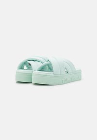 Sandali platform verde menta con design a fascetta incrociata, realizzati in materiale morbido, dotati di suola testurizzata e marchio "TOMMY JEANS" in rilievo.