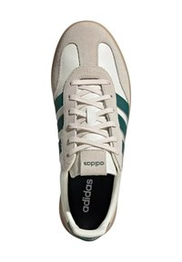 Scarpa sportiva bianca e beige con strisce verdi, con una tomaia in suede, chiusura con lacci e suola in gomma, con il logo adidas.