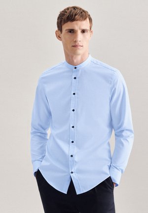 Camicia a maniche lunghe azzurro chiaro con colletto alla mandarino, bottoni neri lungo il davanti e orlo curvo. Tessuto dalla texture liscia.