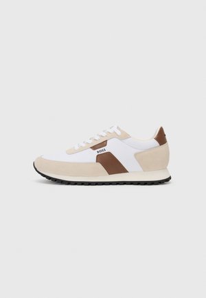 Sneakers featuring a mix of white mesh and beige suede, with a brown leather accent. Rounded toe, flat rubber sole, and lace-up design.