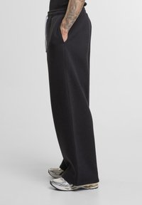 Sorte sweatpants lavet af blødt stof, med en løs pasform, elastisk talje og sidelommer. Sammen med sporty sneakers.
