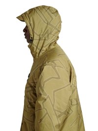 Person im Profil trägt eine hellbraune Kapuzenjacke mit abstrakten geometrischen Mustern und einem Kordelzug am Gesicht.