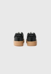 Sorte syntetiske sneakers med såle i gummirubber. Har hvit innside og 'GUESS'-logo på hælen. Enkelt design, lågtopp stil.