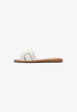 Hvide lædersandal med slidser, to brede stropper, åbent tådesign og flad tan-gummisål. Glat tekstur og minimalistisk stil.