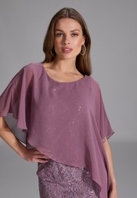 Lavender chiffon top with cape sleeves, featuring sequins on the front. Worn over a matching lace skirt with a scalloped hem.