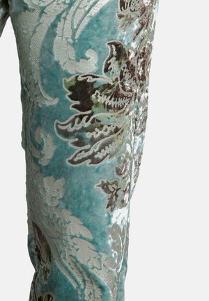 Türkisfarbener Samtstoff mit aufwendigen floralen Mustern in Silber und Braun. Die Textur ist weich und plüschig und zeigt detaillierte Stickereien.