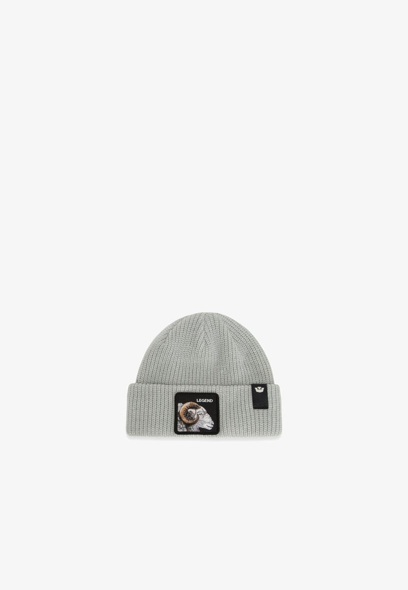 Bonnet en maille côtelée gris clair avec un revers, un écusson représentant un bélier et portant l’inscription « LEGEND », ainsi qu’une petite étiquette noire avec un logo.