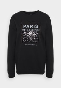 Sudadera negra con un gráfico de lentejuelas que muestra el texto "PARIS ATELIER COUTURE". Puños y dobladillo acanalados, cuello redondo, diseño casual.