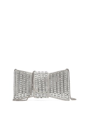 Pochette da sera tono argento a forma di fiocco, completamente ricoperta da file di strass trasparenti e con tracolla a catena.