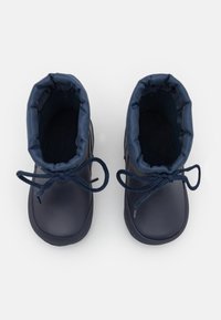 Botas de agua en color navy con una superficie lisa, parte superior elástica y cordones. Punta redondeada y suela texturizada para mayor agarre. El interior cuenta con un forro suave.