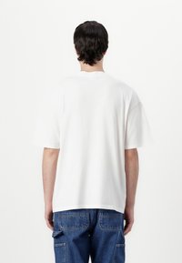 Weißes Baumwoll-T-Shirt mit lässigem Schnitt, kurzen Ärmeln und Rundhalsausschnitt, kombiniert mit blauen Denim-Cargo-Hosen.