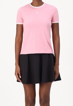 T-shirt en coton rose à manches courtes avec bordure blanche, associé à une jupe noire évasée. Design simple, coupe confortable, sans motifs.