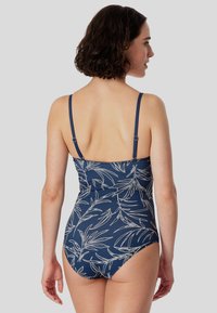 Marine-farbenes Badeanzug-Einteiler mit weißem botanischem Druck, verstellbaren Spaghettiträgern und einem taillierten Design, das eine glatte Textur betont.