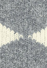 Primo piano di un tessuto grigio a maglia con un motivo di linee bianche a zigzag attraverso il centro.