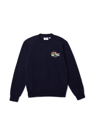 Granatowa bluza z okrągłym dekoltem, długimi rękawami i małą, kolorową naszywką z logo krokodyla Lacoste na lewej piersi.