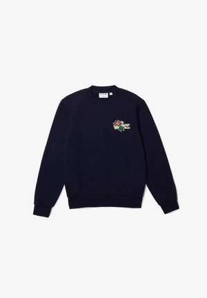 Sweat-shirt bleu marine à col rond avec manches longues et petit patch logo crocodile coloré Lacoste sur la poitrine gauche.