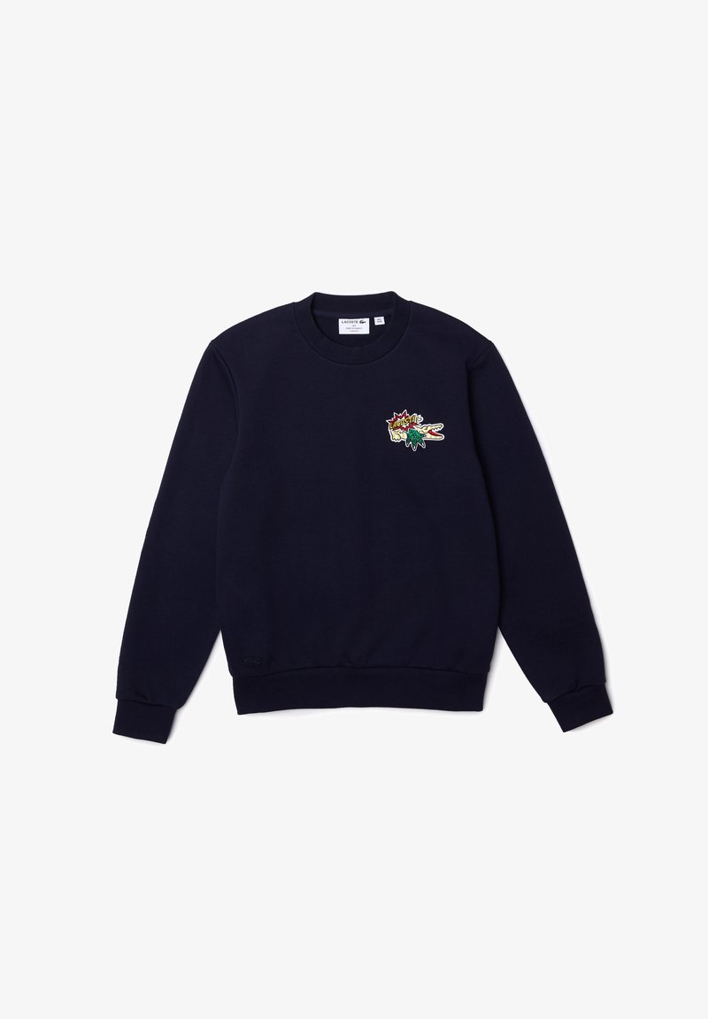 Sweat-shirt bleu marine à col rond avec manches longues et petit patch logo crocodile coloré Lacoste sur la poitrine gauche.