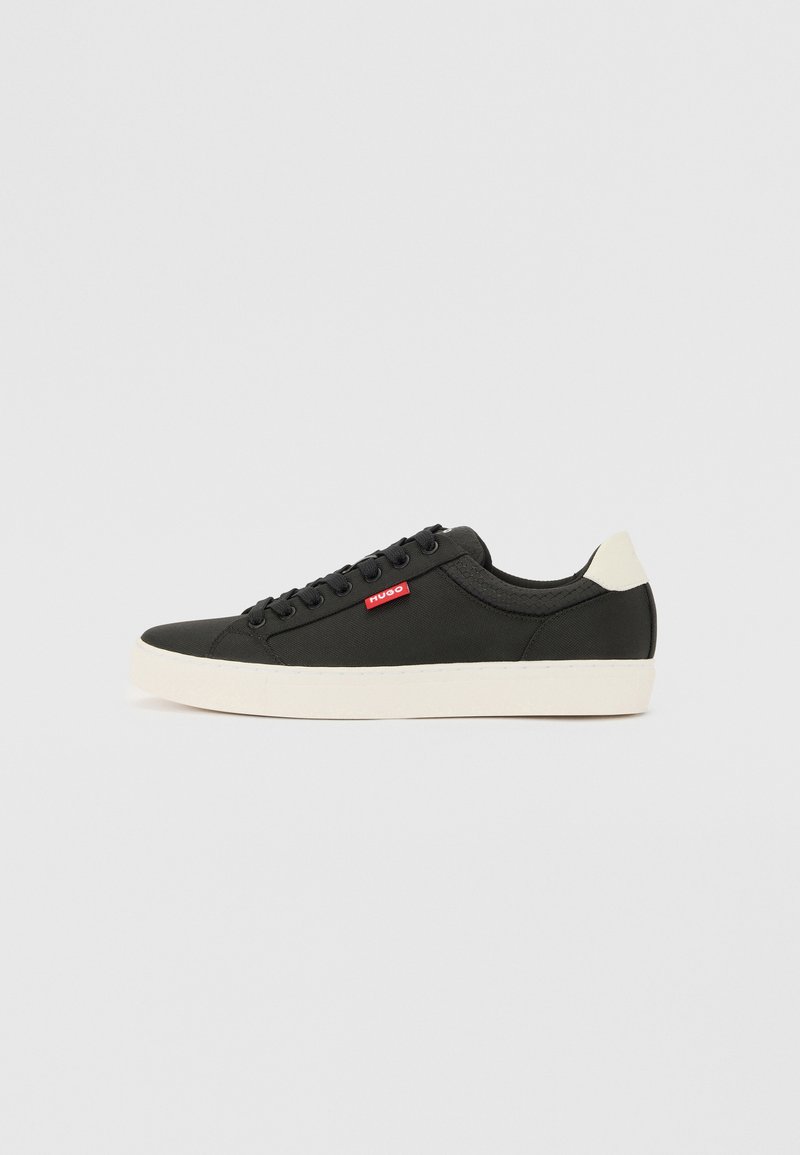 Czarne płócienne sneakersy na białej podeszwie, z czerwonym akcentem logo, okrągłym czubkiem i sześcioma oczkami do sznurowania. Gładka tekstura.