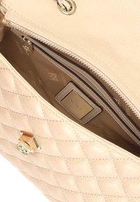 Borsa a tracolla in pelle trapuntata beige con hardware dorato. L'interno presenta una tasca con zip e un'etichetta del marchio su una fodera color panna.