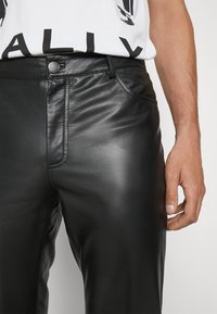 Svarta läderbyxor med en slät yta, framfickor och knappstängning. Den slim-fit designen framhäver silhuetten.