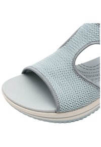 Sandal in tessuto azzurro chiaro con punta aperta, superficie testurizzata, dettagli elasticizzati e suola imbottita con un leggero motivo a scanalature.