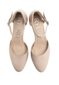 Beżowe buty zakryte z gładkiej skóry, o zaokrąglonym kształcie i pasku wokół kostki. Wnętrze ma teksturowaną wkładkę z logo.