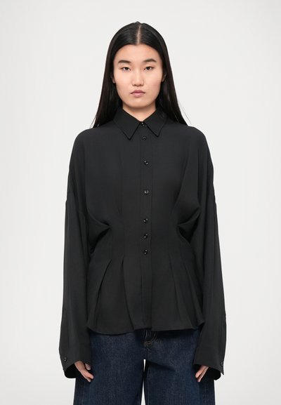 Chemise noire à boutons, fabriquée en tissu léger, avec un col pointu, un design plissé et des manches longues avec des poignets boutonnés.