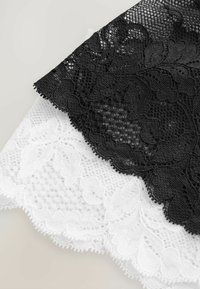 Zwart-witte kantstof met ingewikkelde bloempatronen. Het zwarte kant heeft een gegolfde rand, terwijl het witte kant een textuurdesign heeft.