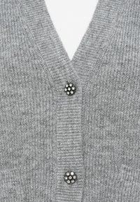 Grau Cardigan mit V-Ausschnitt-Design, das eine gerippte Textur und zwei dekorative Knöpfe mit floralem Muster zeigt. Weiches Material, engmaschig.