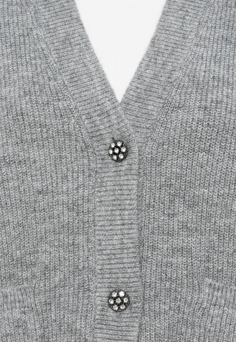 Cardigan grigio con design a V, che mette in mostra una texture a coste e due bottoni decorativi con un motivo floreale. Materiale morbido, a maglia stretta.