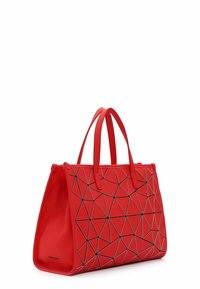 Borsa geometrica rossa con forma strutturata, realizzata in materiale liscio. Presenta motivi triangolari neri e due manici robusti.