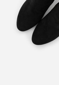 Czarne zamszowe botki za kostkę z ostrym noskiem o gładkiej teksturze, prezentujące elegancką sylwetkę i minimalistyczny design.