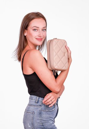 Beige quilted clutch bag with two zipper pulls, featuring diamond patterns. Held in one hand against a plain white background.