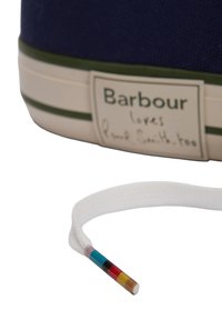 Σόλα παπουτσιού αθλητικού με το κείμενο «Barbour αγαπάει και τον Paul Smith» και λευκό κορδόνι με πολύχρωμη, ριγέ μύτη κορδονιού.