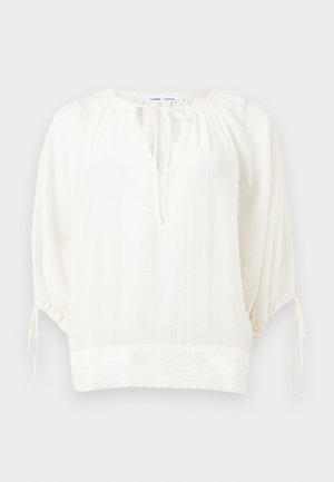 Bílá volná halenka s 3/4 nabíranými rukávy, kulatým výstřihem se zavazováním a nařasenými detaily na ramenou a manžetách.