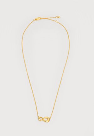 Collier délicat en chaîne d'or avec un petit pendentif symbole infini poli et une fermeture à boucle réglable sur fond blanc.