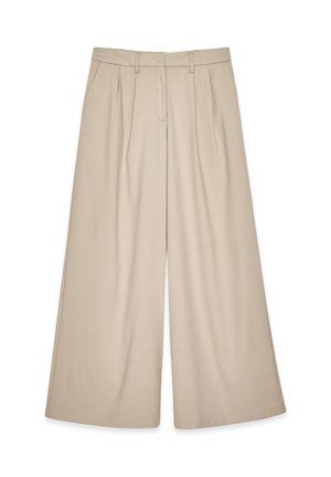 Pantalons larges beiges à taille haute, avec des plis avant et une texture lisse. Conçus pour un ajustement décontracté avec un look soigné.