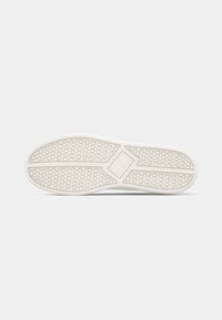 Semelle de chaussure blanche avec motif de bande de roulement hexagonal et un dessin central en forme de losange sur fond uni.