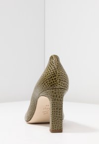 Chaussure à talons hauts en simili cuir vert avec un motif reptilien texturé, bout pointu et un talon robuste. Doublure intérieure neutre.
