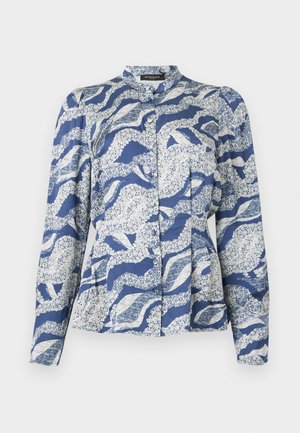 Blusa azul con un patrón de olas en blanco, con frente abotonado, cuello redondeado y mangas largas. Hecha de una tela texturizada.