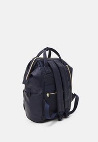 Sac à dos en cuir bleu marine avec deux poignées supérieures et des bretelles rembourrées. Doté de zips dorés et de plusieurs poches externes.