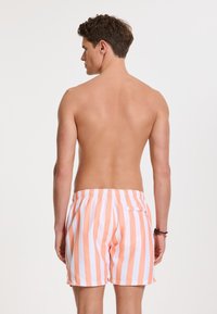 Csíkos fürdőshorts világos narancs és fehér színben, szintetikus anyagból, rugalmas derékpánttal és hátsó zsebbel.