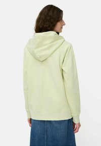Jasnozielona bluza z dużym kapturem, ściągaczami przy mankietach i u dołu, pokazana z tyłu. Gładka tekstura, casualowy design, w zestawieniu z dżinsową spódnicą.