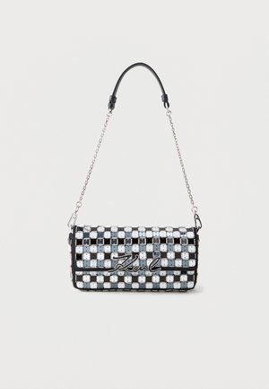 Bolso de mano a cuadros en blanco y negro con tachuelas plateadas, una correa de cadena metálica y la firma "Karl" en la solapa frontal.
