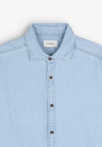 Lyseblå denimskjorte med knapkrave, udstyret med brune knapper og et mærke med "SCALPERS." Glat tekstur, afslappet design.