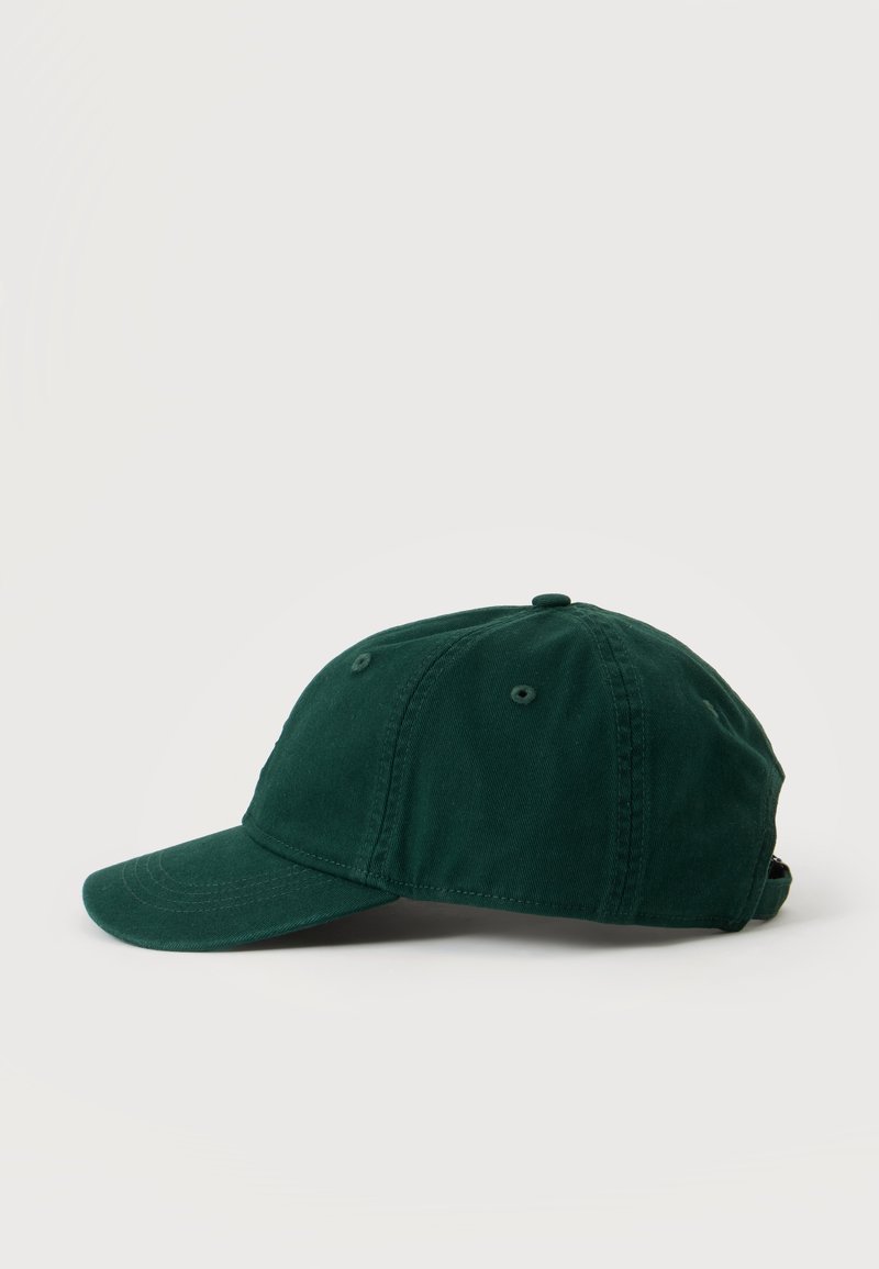 Cappellino da baseball a sei pannelli verde scuro con occhielli cuciti e visiera curva su uno sfondo chiaro uniforme.